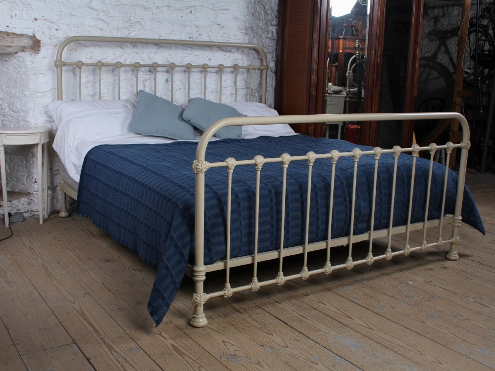 A cream-painted French iron super king size bed frame featuring vertical spindles and cast iron ornamental details.