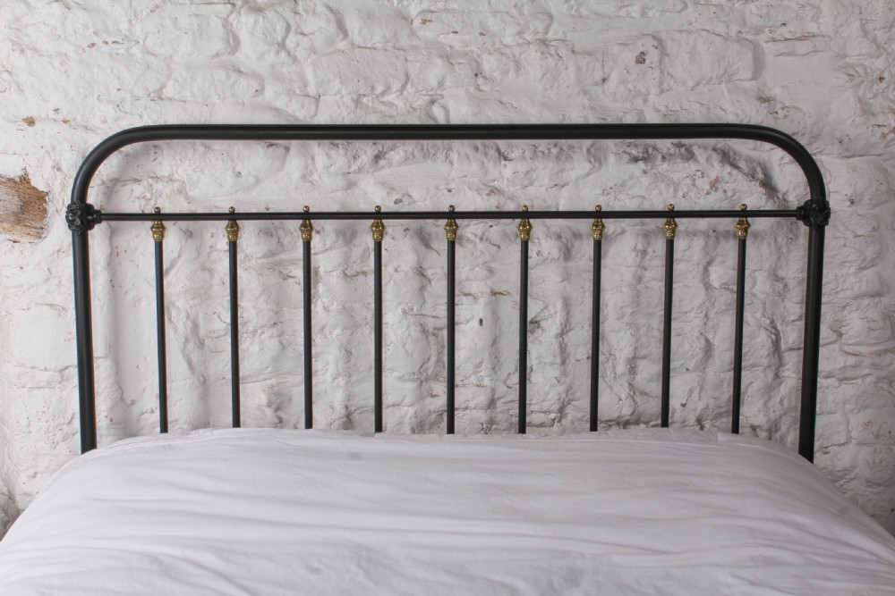 A king size black painted iron bedstead featuring rounded top rails, vertical tubular spindles, and decorative brass finials. View III