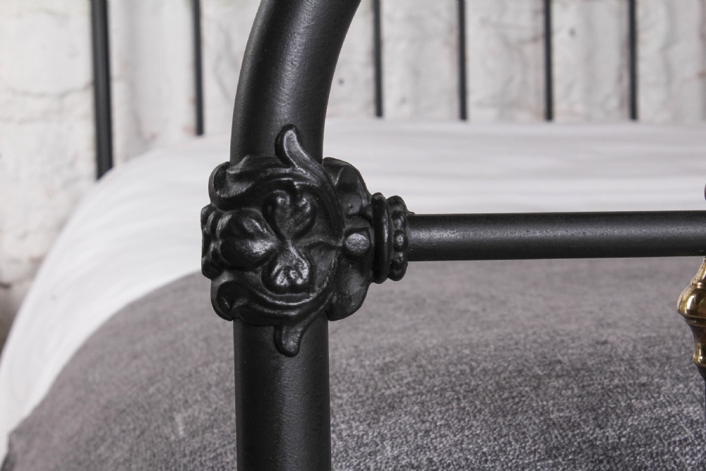 A king size black painted iron bedstead featuring rounded top rails, vertical tubular spindles, and decorative brass finials. View IV