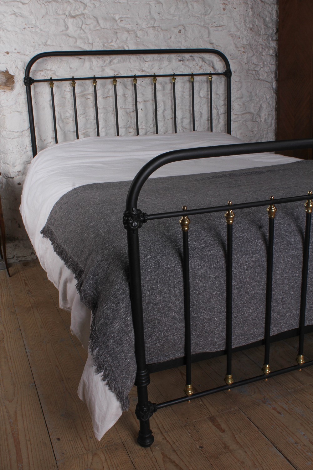 A king size black painted iron bedstead featuring rounded top rails, vertical tubular spindles, and decorative brass finials. View VI