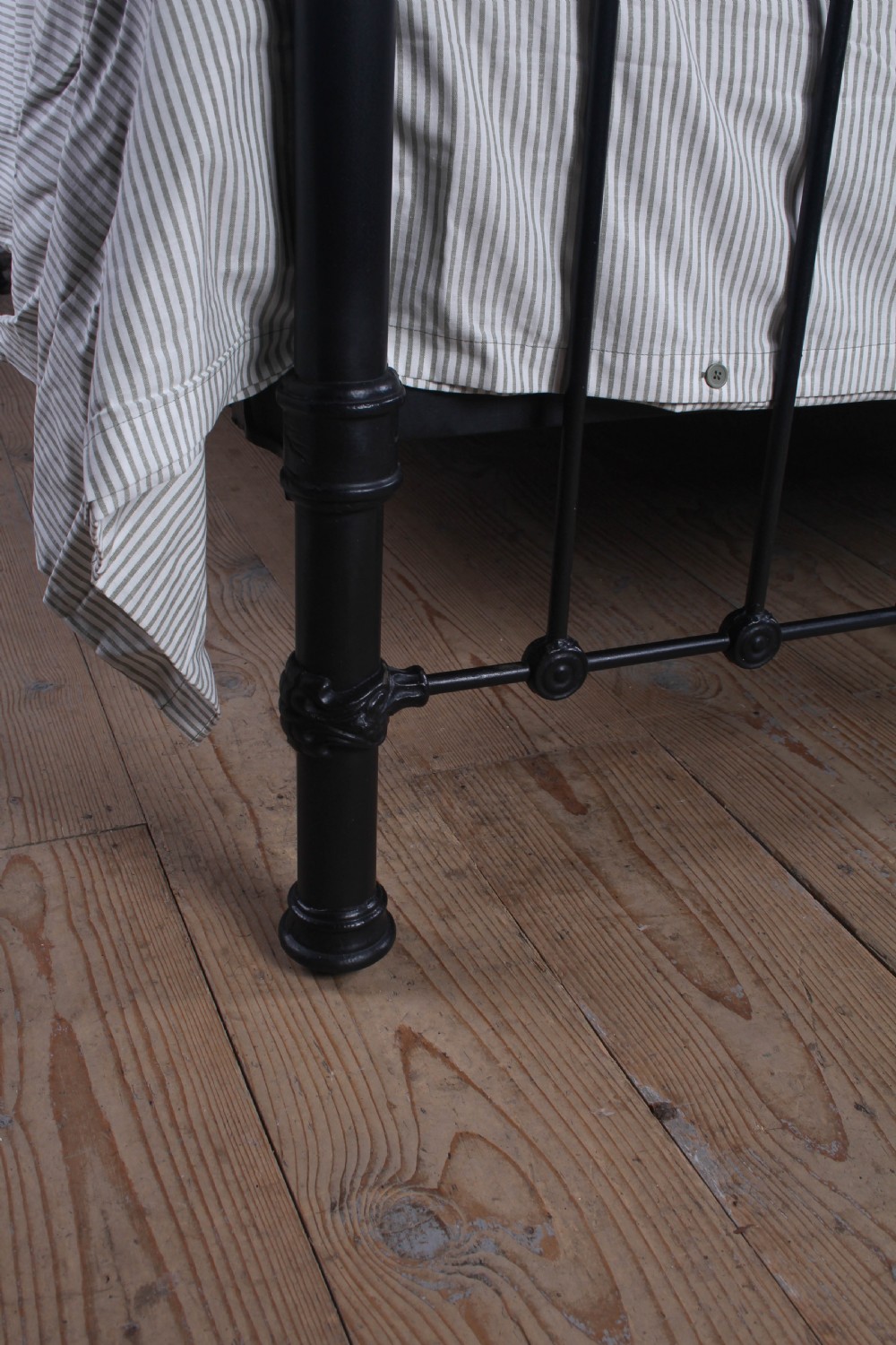 A Victorian black iron and brass super king-size bedstead featuring vertical spindles, circular brass medallions on the footboard, and brass top rails with spherical finials. View XI