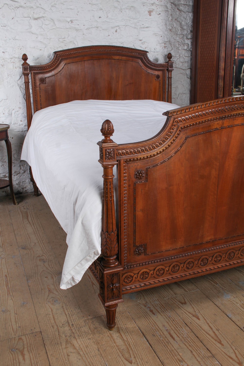A carved walnut king-size bedstead featuring an arched headboard and footboard framed by fluted corner posts and decorative finials. View II