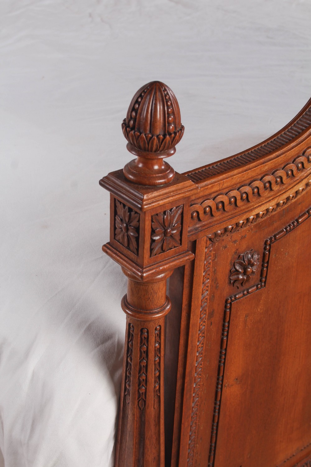 A carved walnut king-size bedstead featuring an arched headboard and footboard framed by fluted corner posts and decorative finials. View V