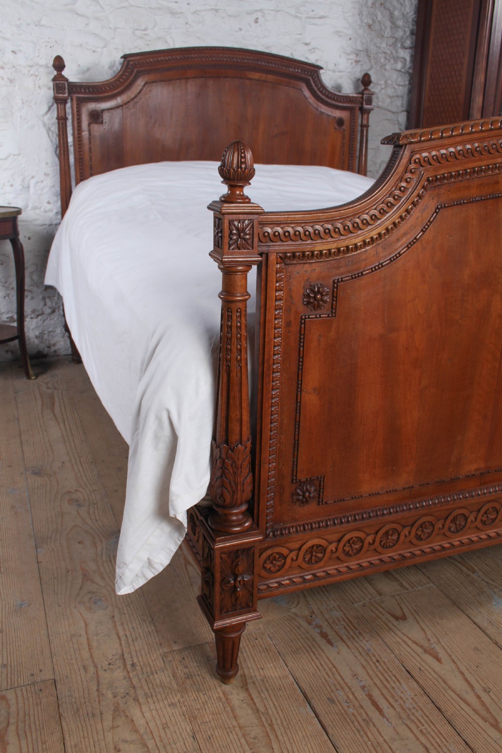 A carved walnut king-size bedstead featuring an arched headboard and footboard framed by fluted corner posts and decorative finials. View VII