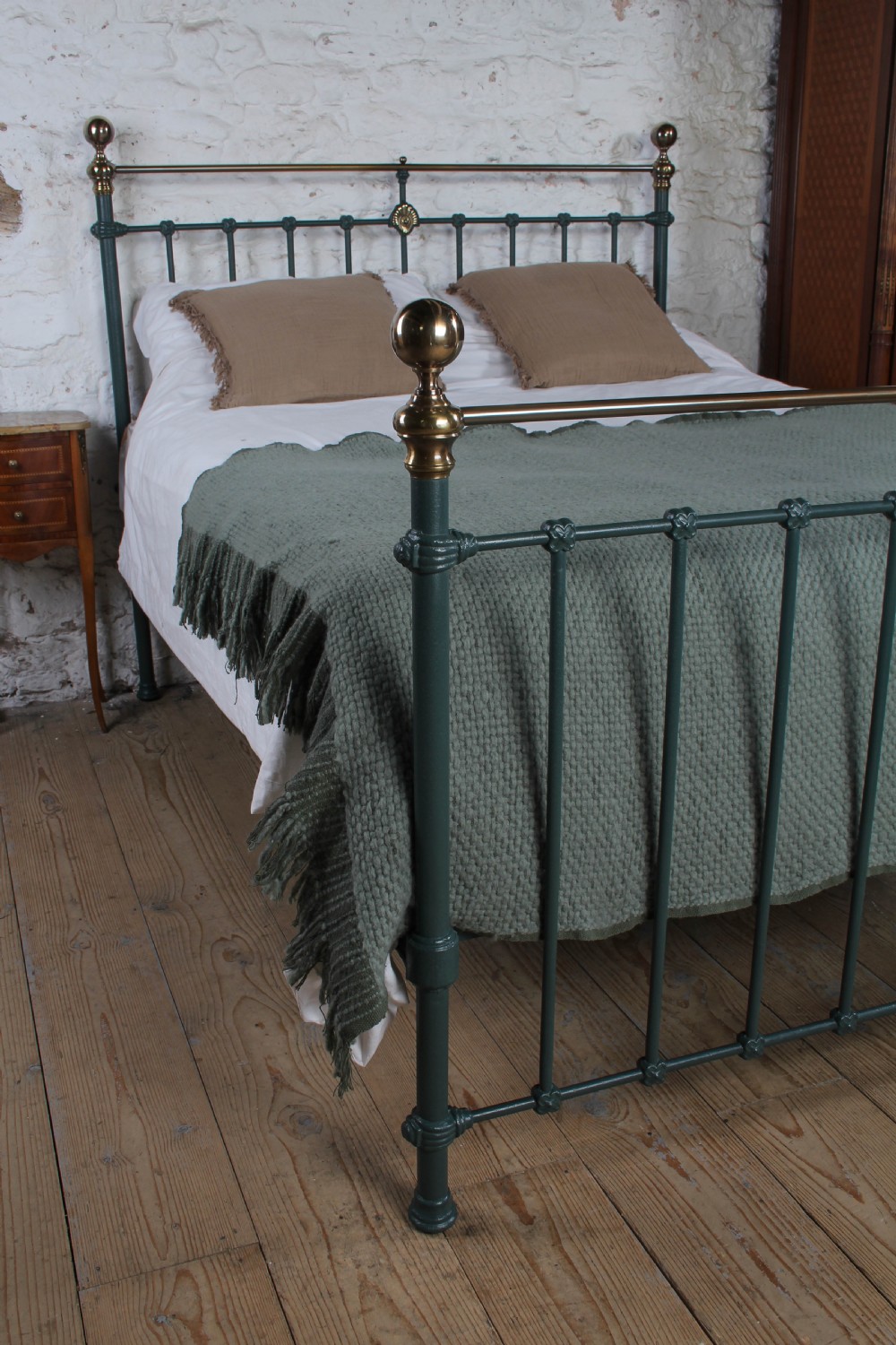 A Victorian metal bedstead featuring dark green painted iron uprights, vertical spindles, brass top rails, and brass finials. View III