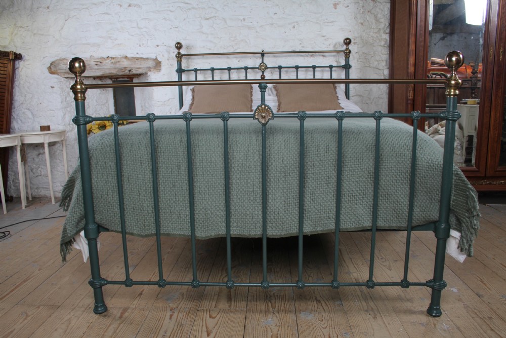 A Victorian metal bedstead featuring dark green painted iron uprights, vertical spindles, brass top rails, and brass finials. View IV