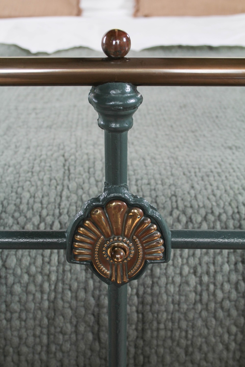 A Victorian metal bedstead featuring dark green painted iron uprights, vertical spindles, brass top rails, and brass finials. View V