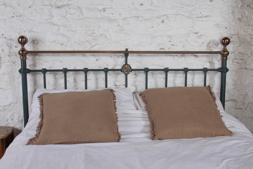 A Victorian metal bedstead featuring dark green painted iron uprights, vertical spindles, brass top rails, and brass finials. View VI