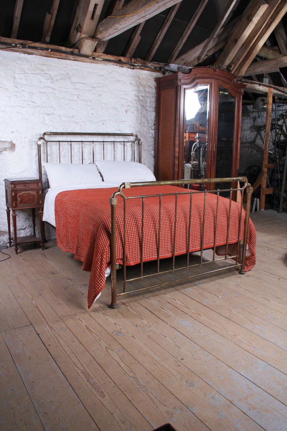 An antique brass king-size bedstead with vertical spindles, rounded tubular top rails, and cast iron corner connections. View II