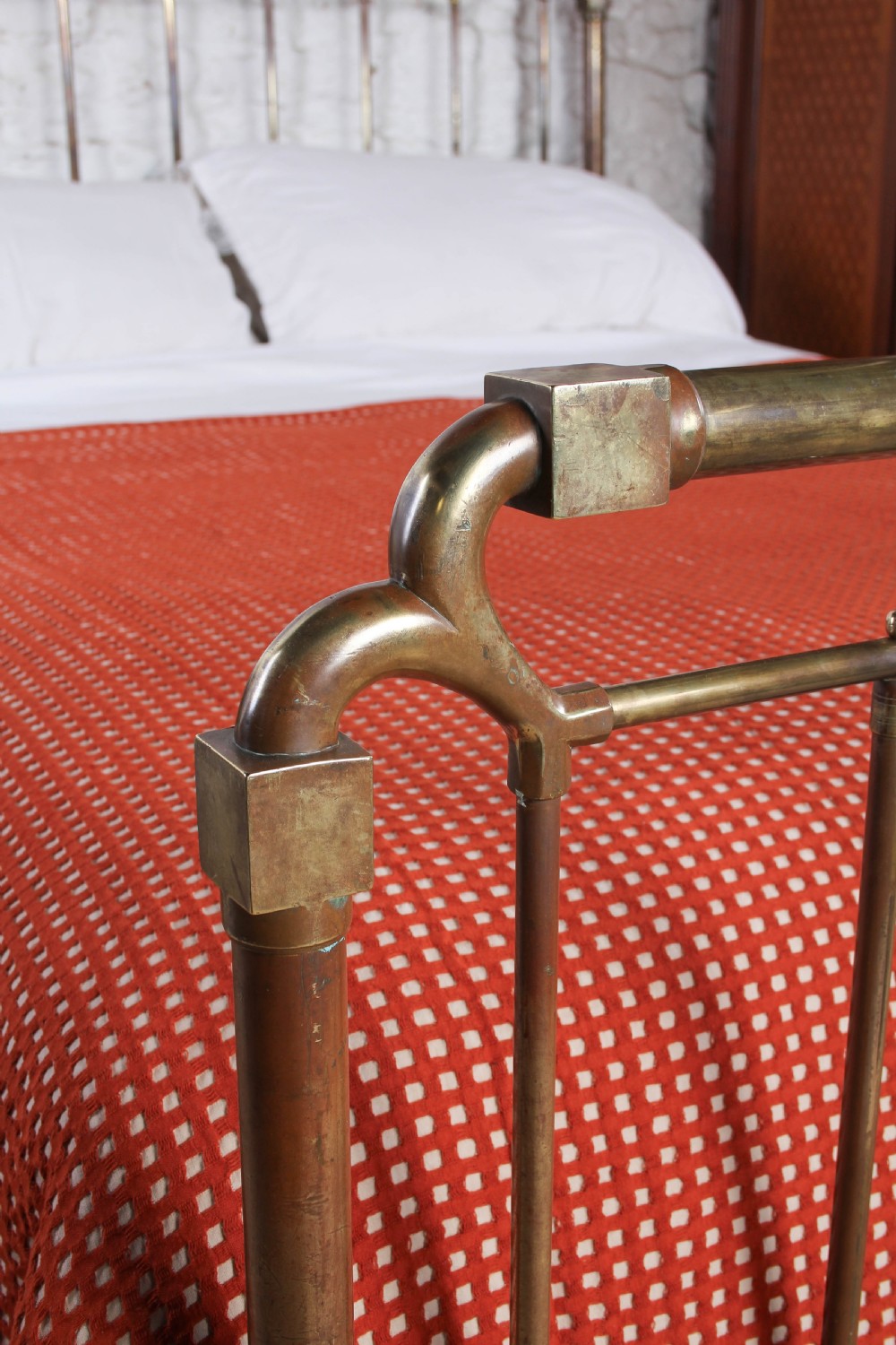 An antique brass king-size bedstead with vertical spindles, rounded tubular top rails, and cast iron corner connections. View IV
