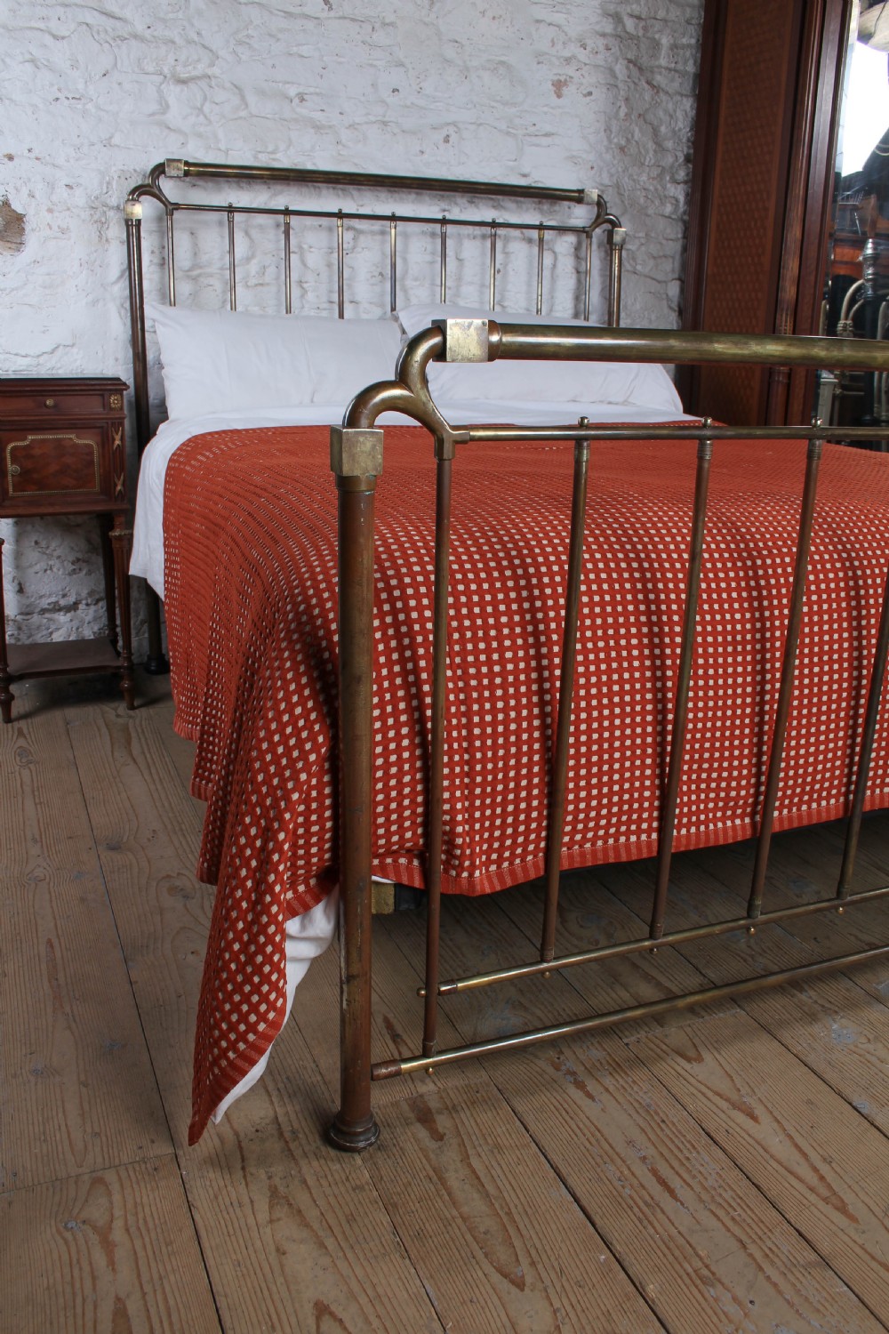 An antique brass king-size bedstead with vertical spindles, rounded tubular top rails, and cast iron corner connections. View VII