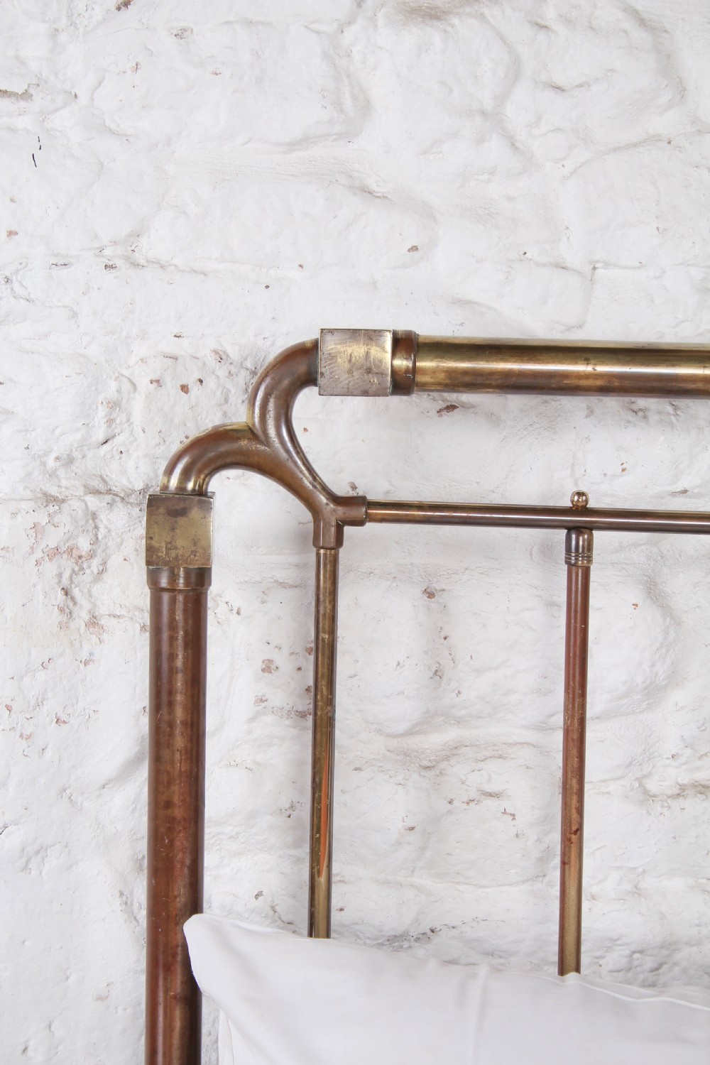 An antique brass king-size bedstead with vertical spindles, rounded tubular top rails, and cast iron corner connections. View IX