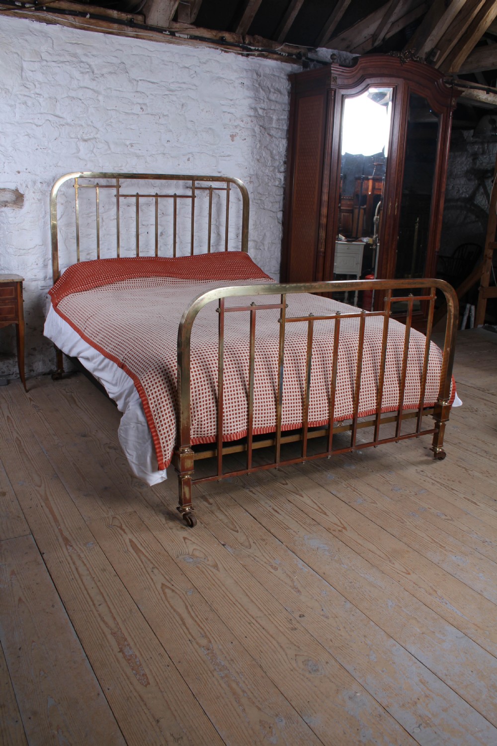 An antique French brass king-size bedstead featuring a square tube frame, rounded top corners, vertical spindles, and brass castors. View II