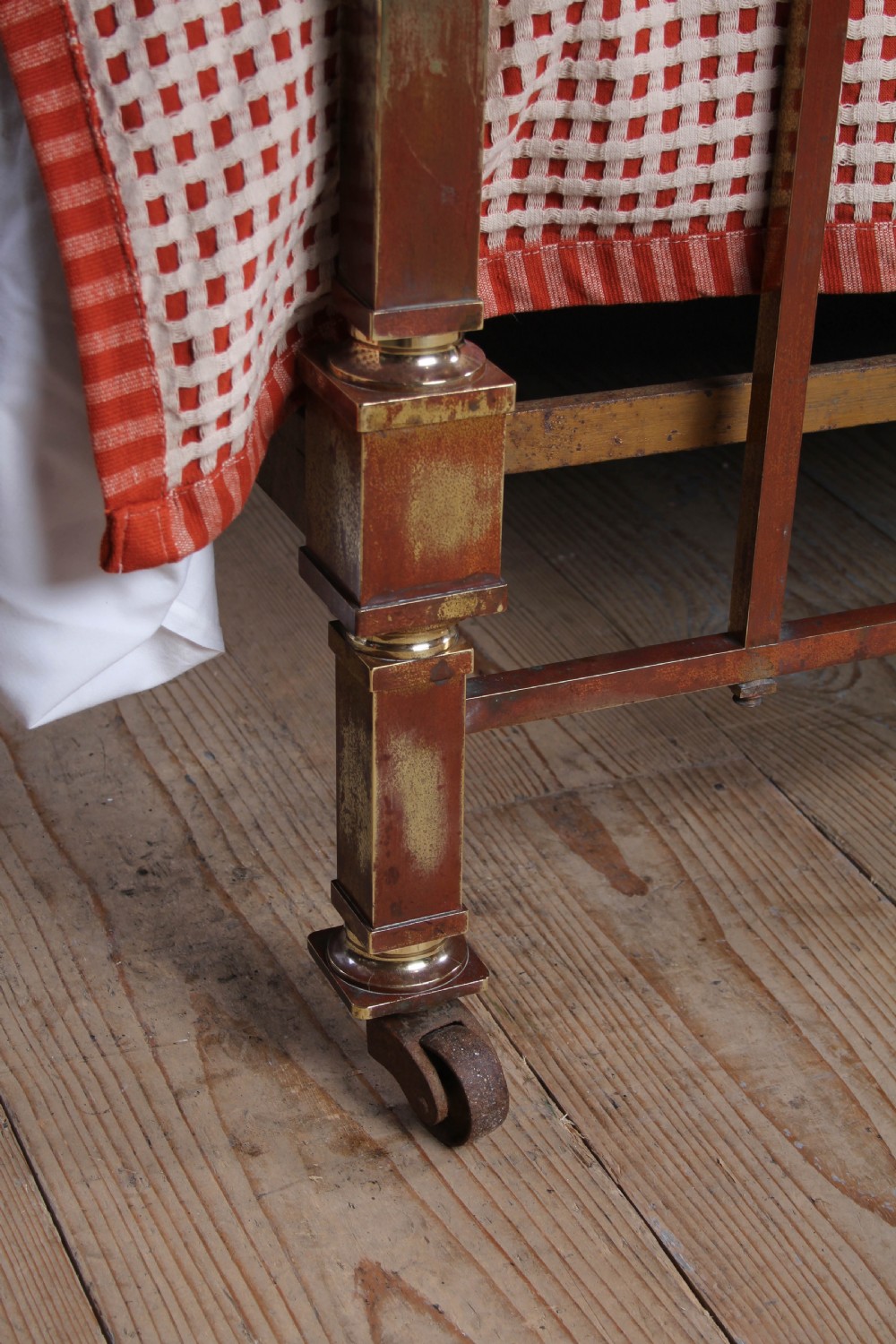 An antique French brass king-size bedstead featuring a square tube frame, rounded top corners, vertical spindles, and brass castors. View III