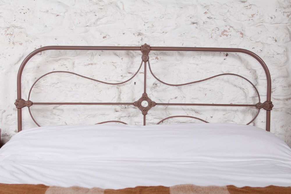 An antique Irish double bed frame constructed from painted iron with curved metal scrollwork and decorative cast medallions. View III