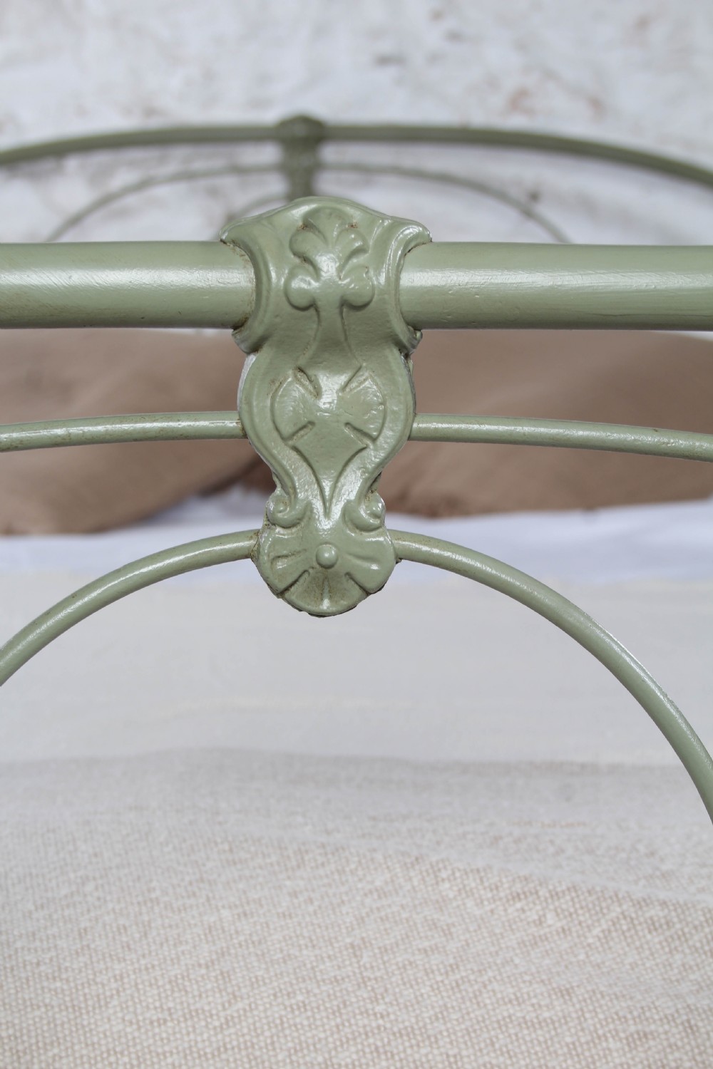 A green painted iron bedstead featuring arched headboard and footboard frames with decorative looped ironwork and cast medallions. View IV