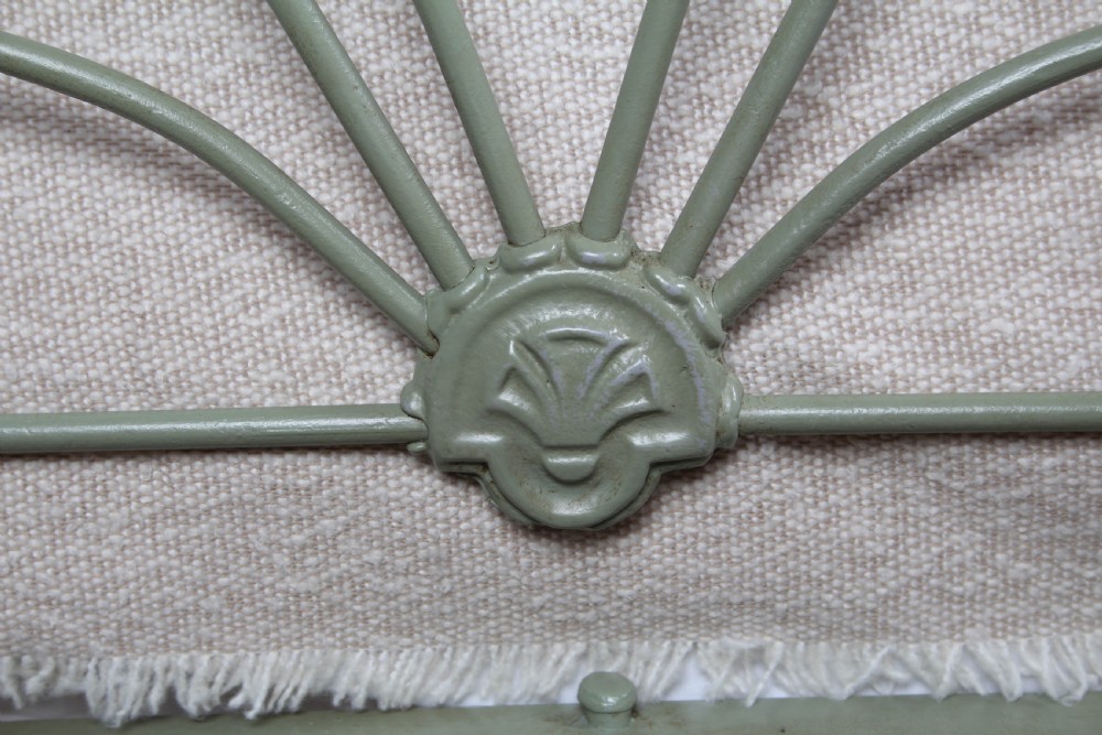 A green painted iron bedstead featuring arched headboard and footboard frames with decorative looped ironwork and cast medallions. View V