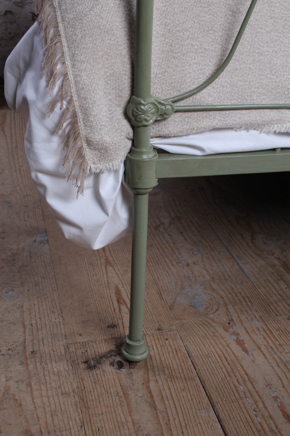A green painted iron bedstead featuring arched headboard and footboard frames with decorative looped ironwork and cast medallions. View VII