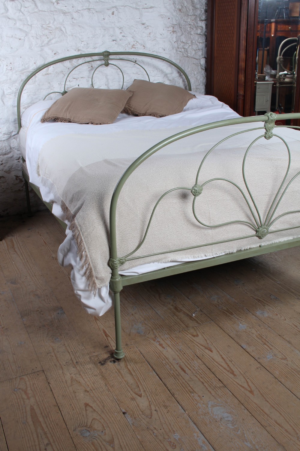 A green painted iron bedstead featuring arched headboard and footboard frames with decorative looped ironwork and cast medallions. View VIII