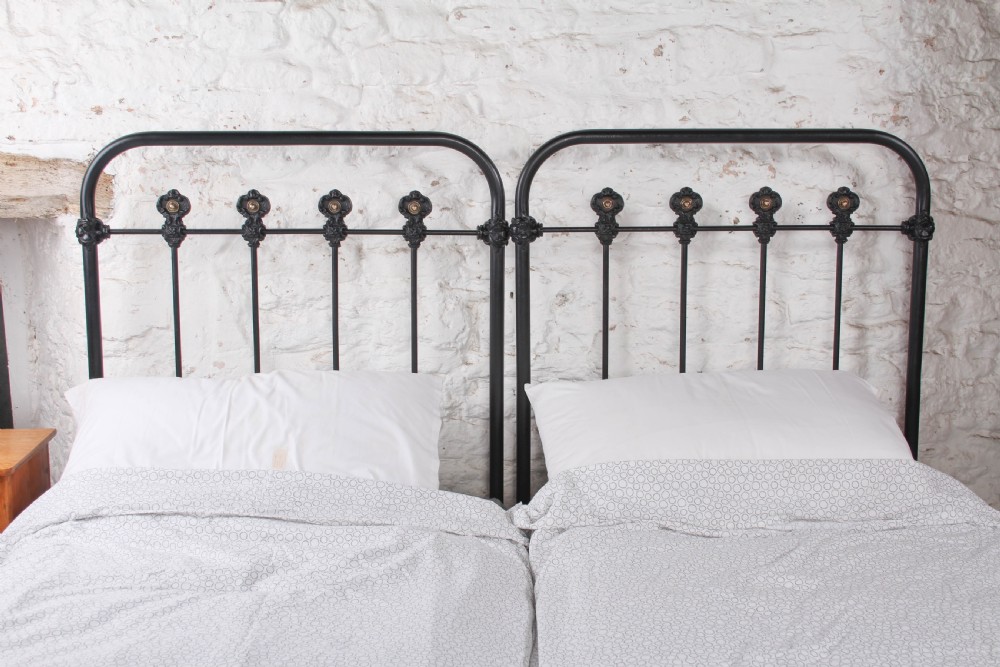 A pair of black wrought iron French single bed frames featuring vertical spindles with cast decorative rosettes and no footboards. View II