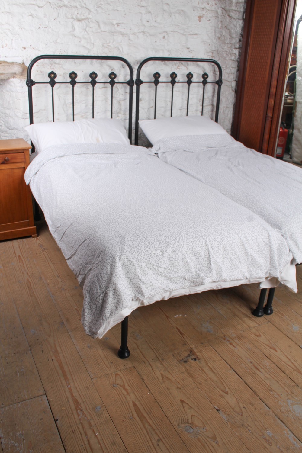 A pair of black wrought iron French single bed frames featuring vertical spindles with cast decorative rosettes and no footboards. View IV
