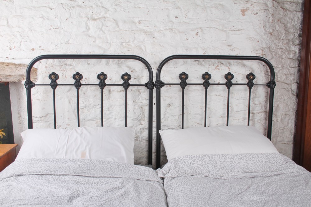 A pair of black wrought iron French single bed frames featuring vertical spindles with cast decorative rosettes and no footboards. View VI