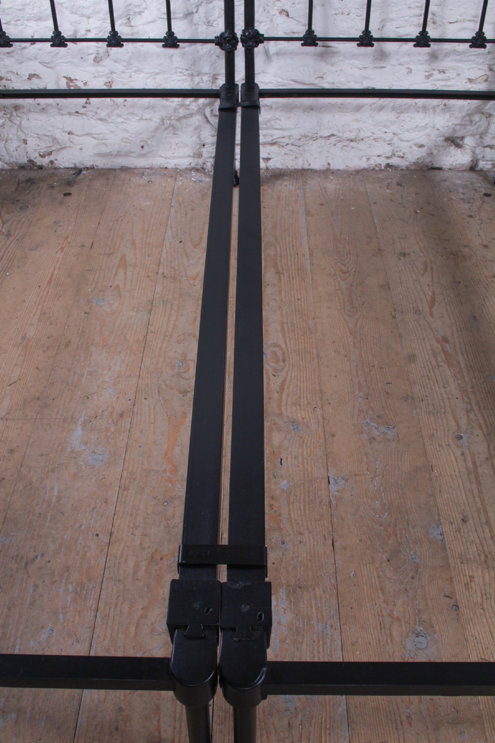 A pair of black wrought iron French single bed frames featuring vertical spindles with cast decorative rosettes and no footboards. View X
