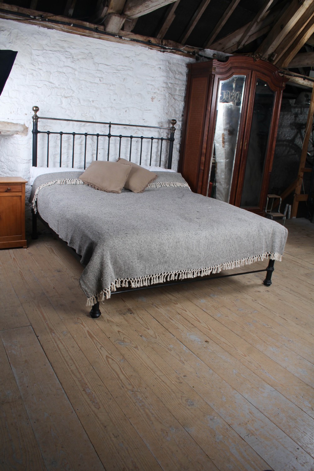A super king size black iron bed frame featuring vertical spindles, a brass top rail, and round brass finials. View II