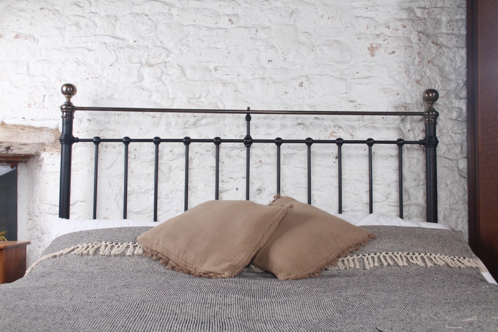 A super king size black iron bed frame featuring vertical spindles, a brass top rail, and round brass finials. View III