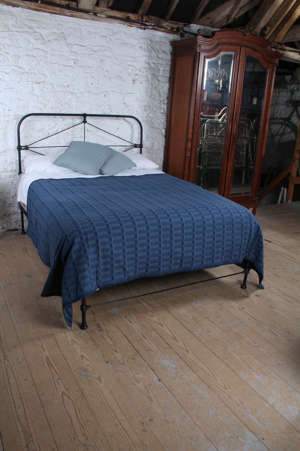 A Victorian black iron king-size bedstead featuring a rounded headboard frame decorated with geometric Celtic strapwork and cast iron bosses. View II