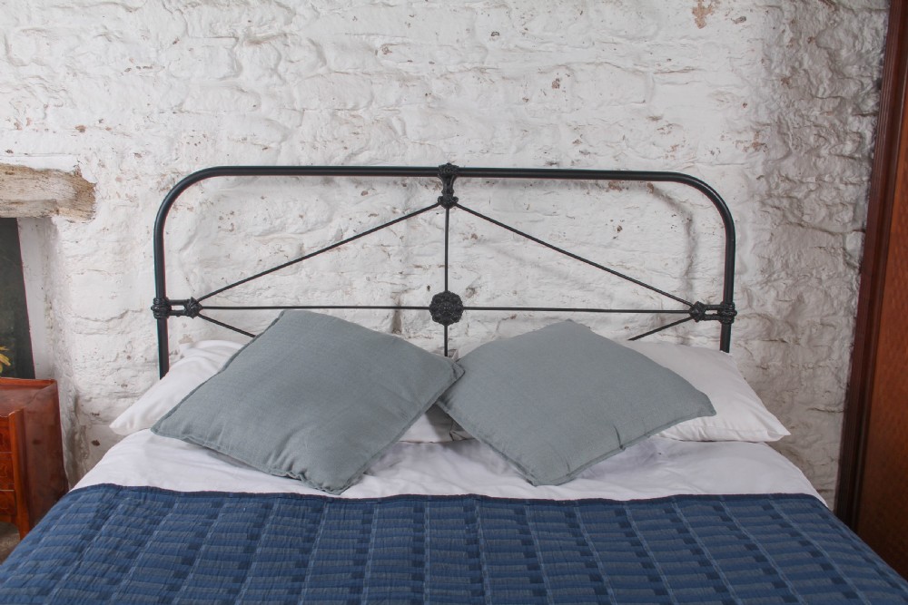 A Victorian black iron king-size bedstead featuring a rounded headboard frame decorated with geometric Celtic strapwork and cast iron bosses. View III