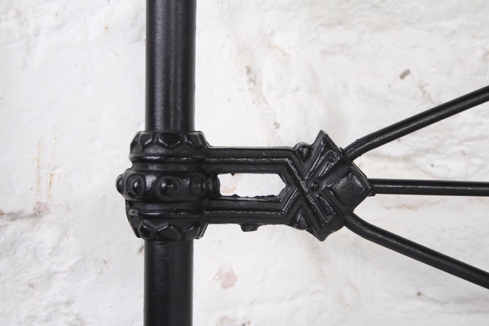 A Victorian black iron king-size bedstead featuring a rounded headboard frame decorated with geometric Celtic strapwork and cast iron bosses. View V