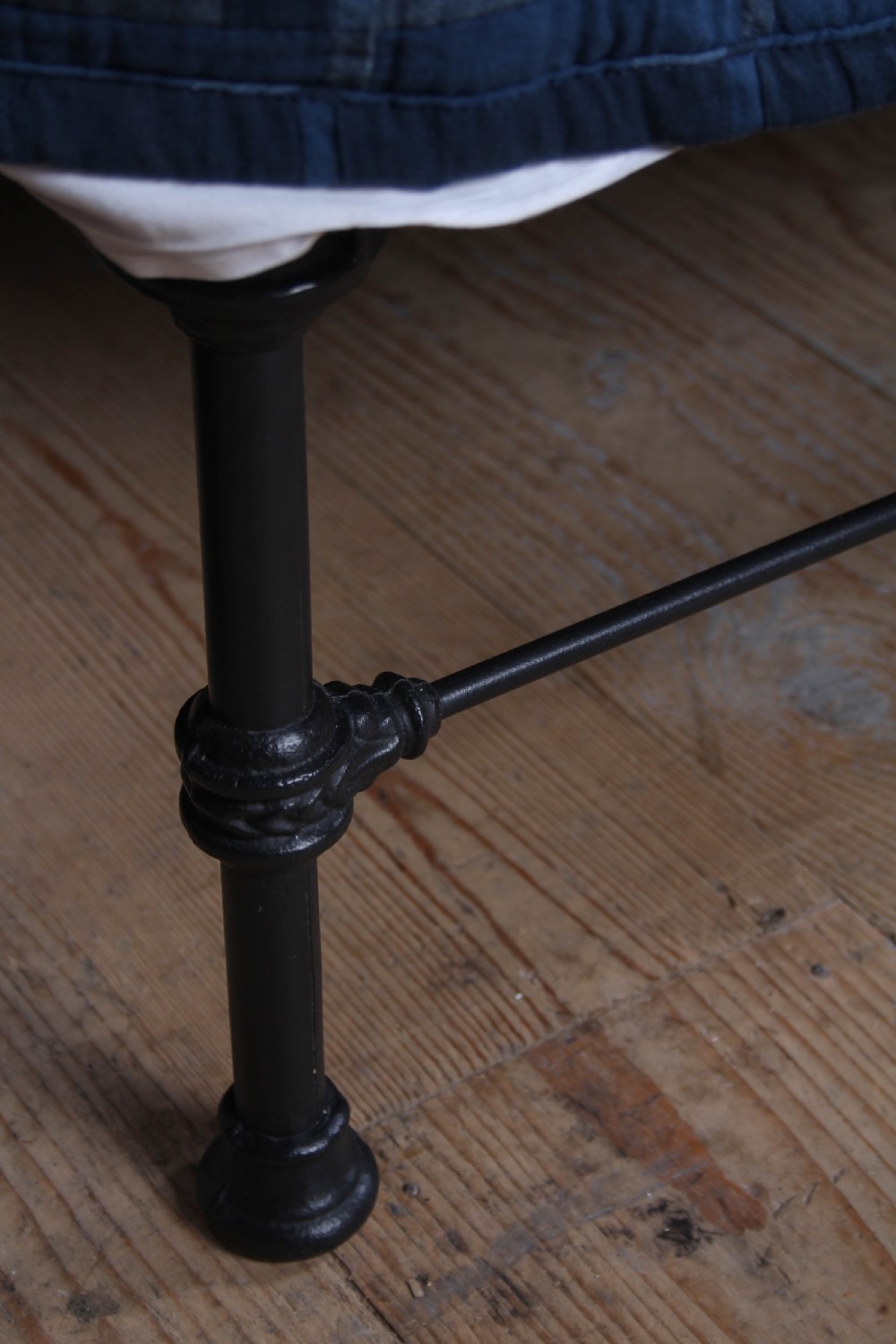 A Victorian black iron king-size bedstead featuring a rounded headboard frame decorated with geometric Celtic strapwork and cast iron bosses. View VI