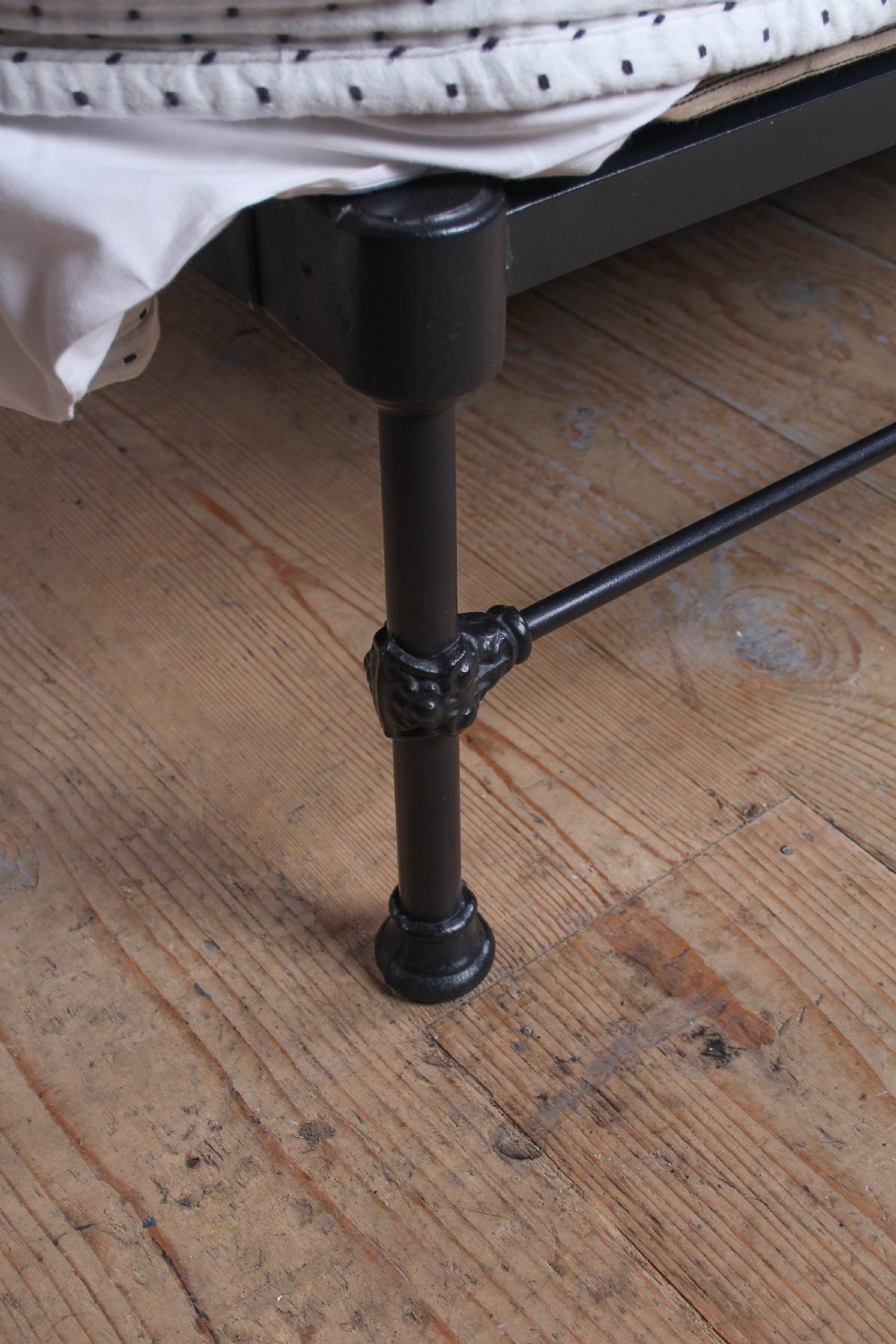 A king size black iron bed frame featuring a spindle headboard with brass roundels and a low foot end. View III