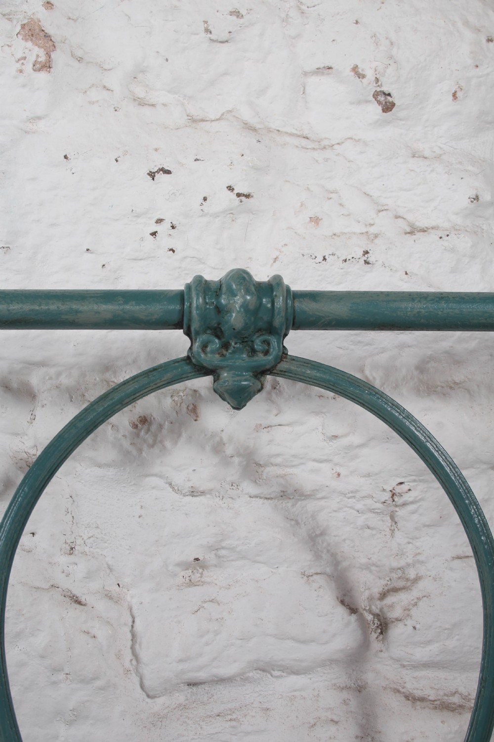 A pair of green painted iron single bed frames featuring scrolled Celtic heart motifs on the headboards and low open ends. View V