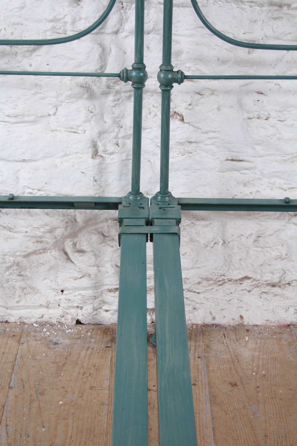 A pair of green painted iron single bed frames featuring scrolled Celtic heart motifs on the headboards and low open ends. View VIII