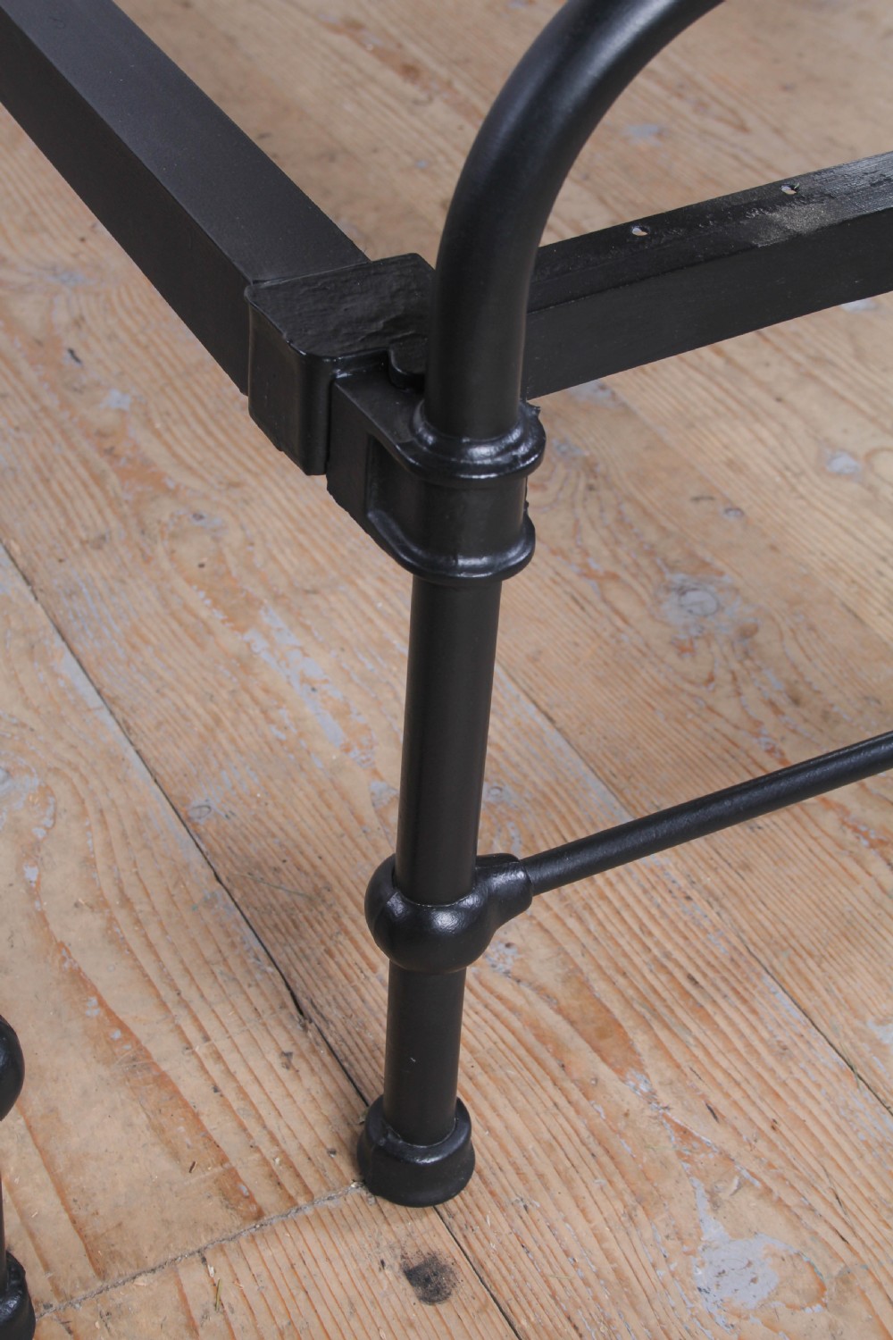 A pair of black painted tubular metal single bed frames featuring simplified vertical headboard spindles. View V