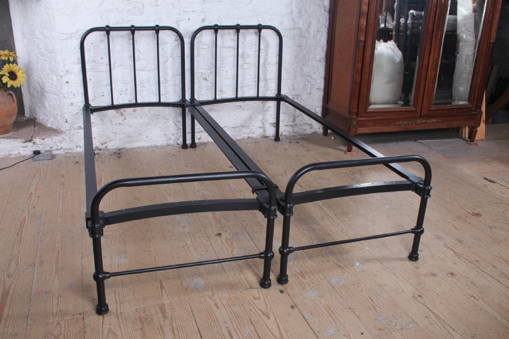 A pair of black painted tubular metal single bed frames featuring simplified vertical headboard spindles. View VIII