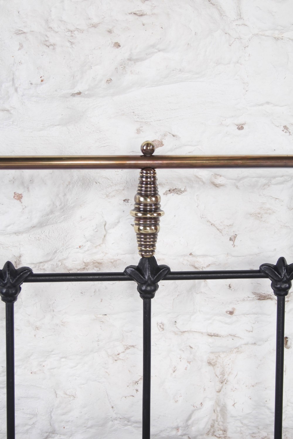 A Victorian black iron king-size bed frame featuring vertical headboard spindles, a brass top rail, decorative brass finials, and a low foot end. View III