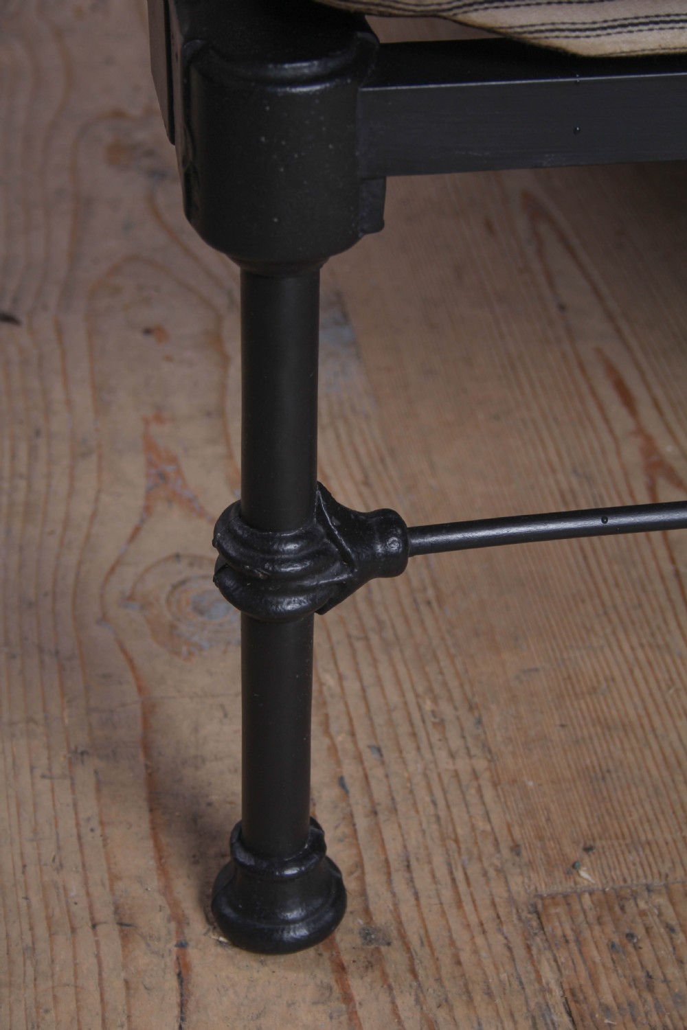 A Victorian black iron king-size bed frame featuring vertical headboard spindles, a brass top rail, decorative brass finials, and a low foot end. View V