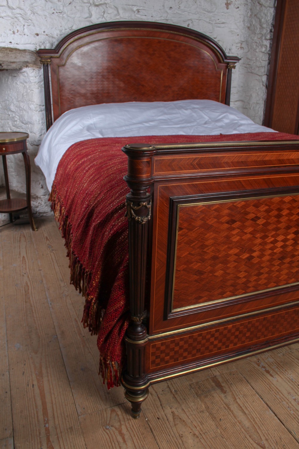 A French king-size bed frame featuring mahogany and fruitwood geometric parquetry inlay, arched headboard, brass trim, and fluted corner posts. View IV