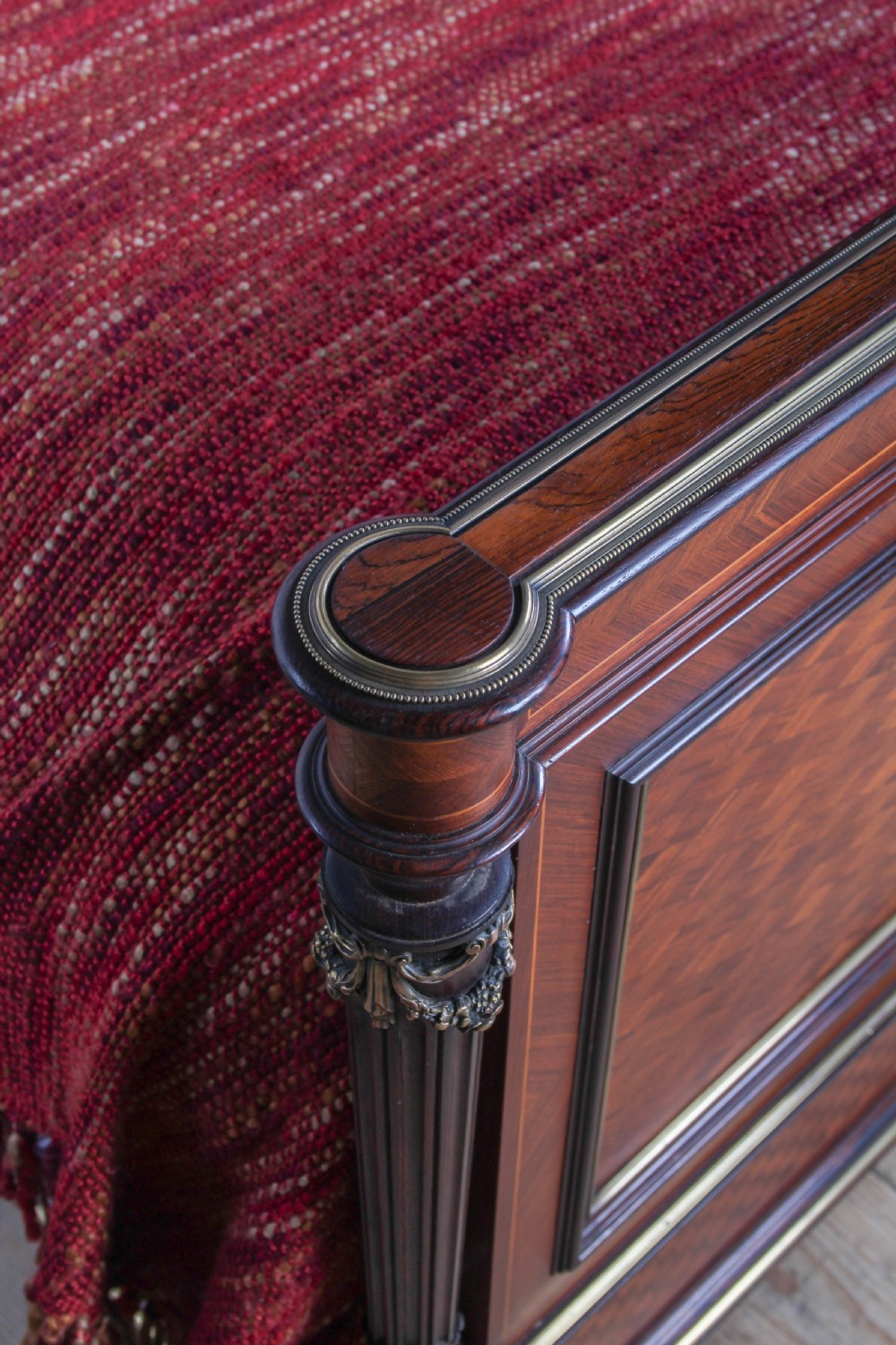 A French king-size bed frame featuring mahogany and fruitwood geometric parquetry inlay, arched headboard, brass trim, and fluted corner posts. View VII
