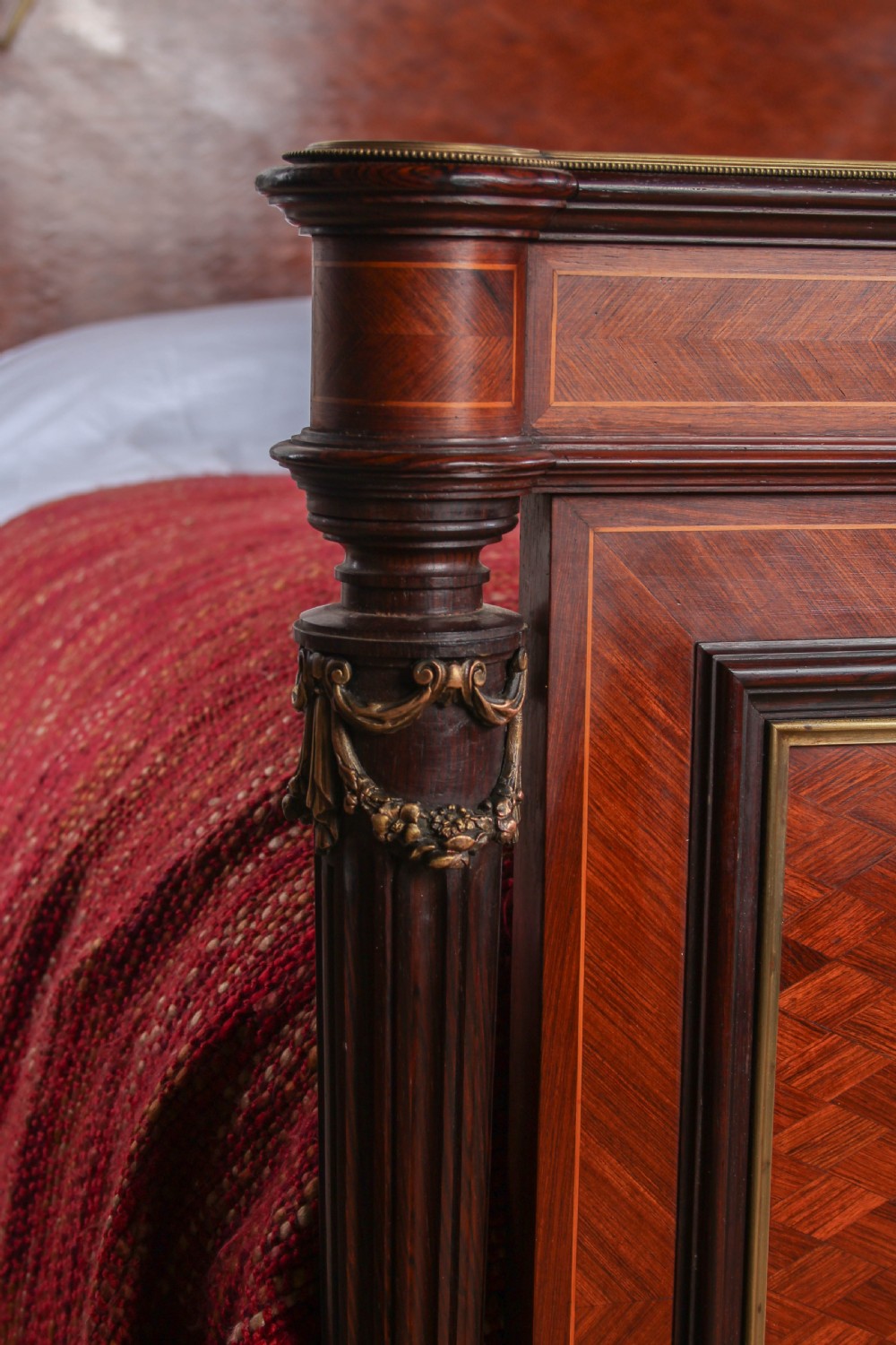 A French king-size bed frame featuring mahogany and fruitwood geometric parquetry inlay, arched headboard, brass trim, and fluted corner posts. View XI
