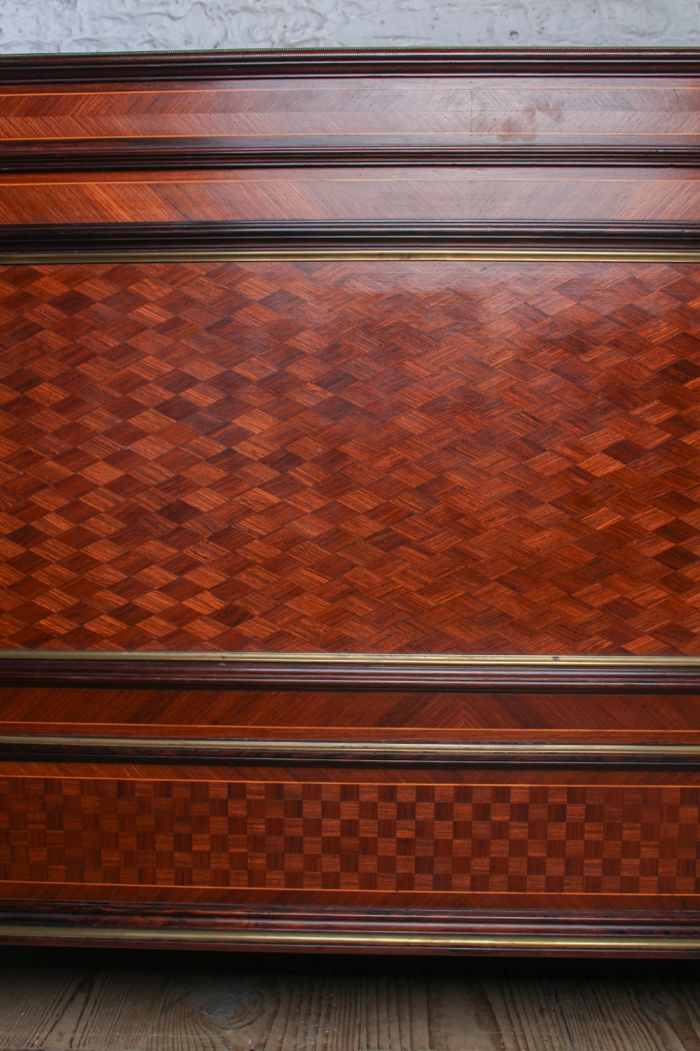 A French king-size bed frame featuring mahogany and fruitwood geometric parquetry inlay, arched headboard, brass trim, and fluted corner posts. View XII