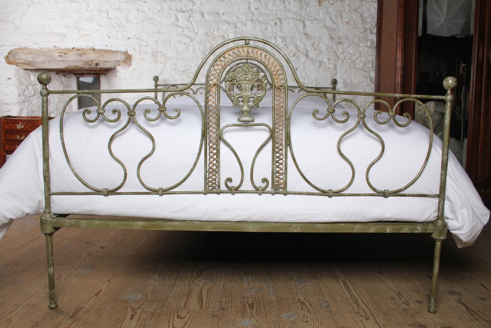 A king-size Portuguese wrought iron bed frame featuring an ornate arched headboard and footboard with central decorative medallions and a distressed green paint finish. View II