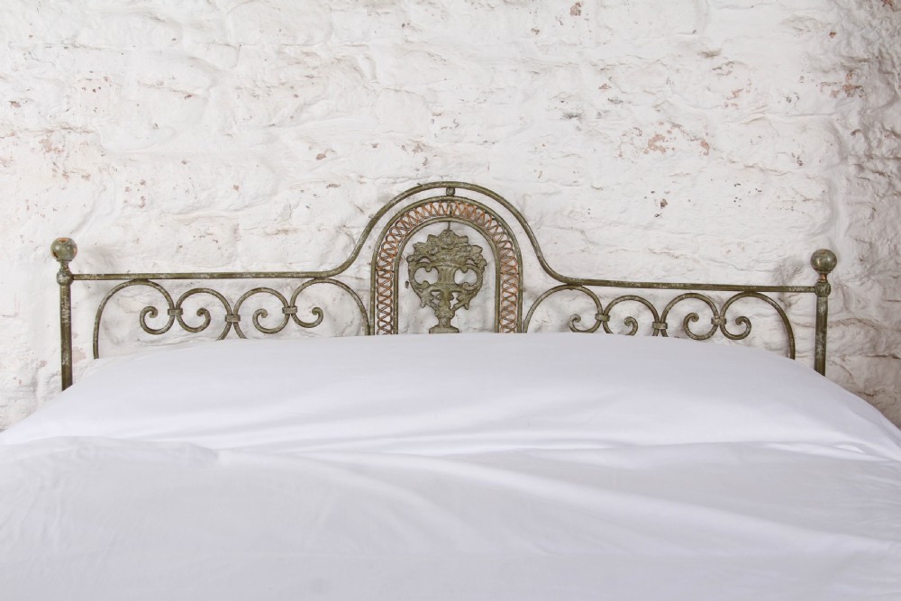 A king-size Portuguese wrought iron bed frame featuring an ornate arched headboard and footboard with central decorative medallions and a distressed green paint finish. View VI