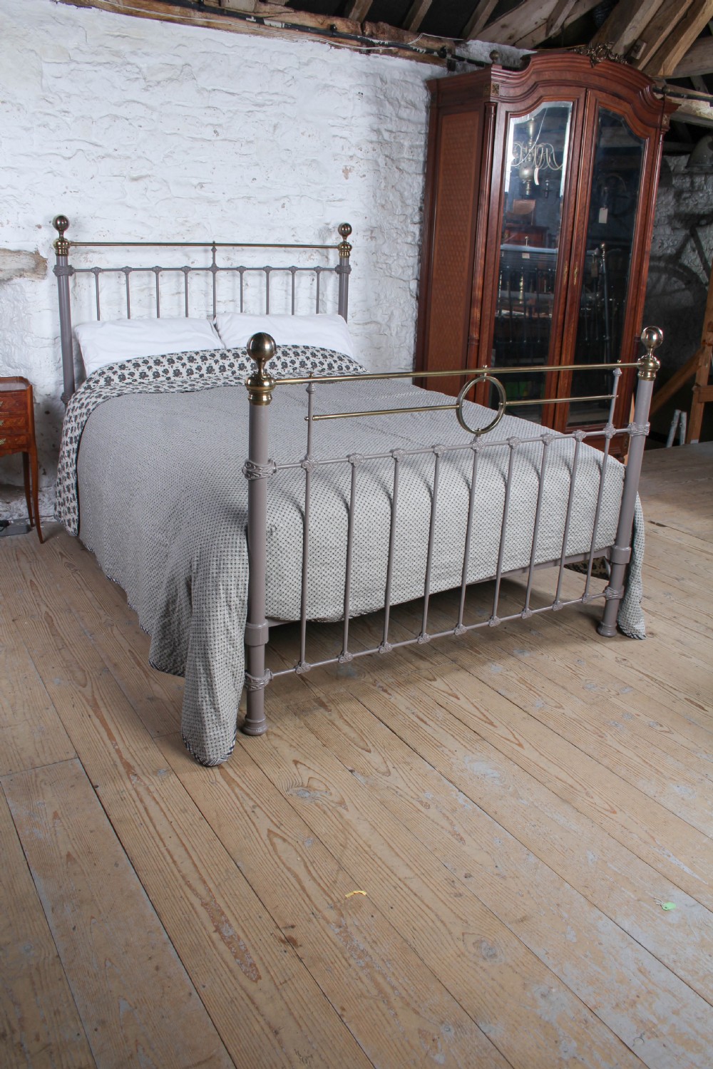 A Victorian cast iron and brass king size bedstead featuring vertical spindles, decorative brass finials, and a grey painted frame. View II