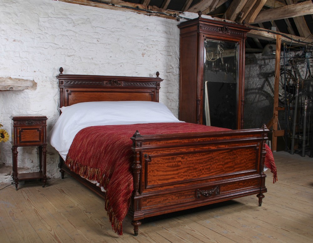 A French Louis XVI style carved mahogany king size bedstead with flame mahogany panelled footboard.