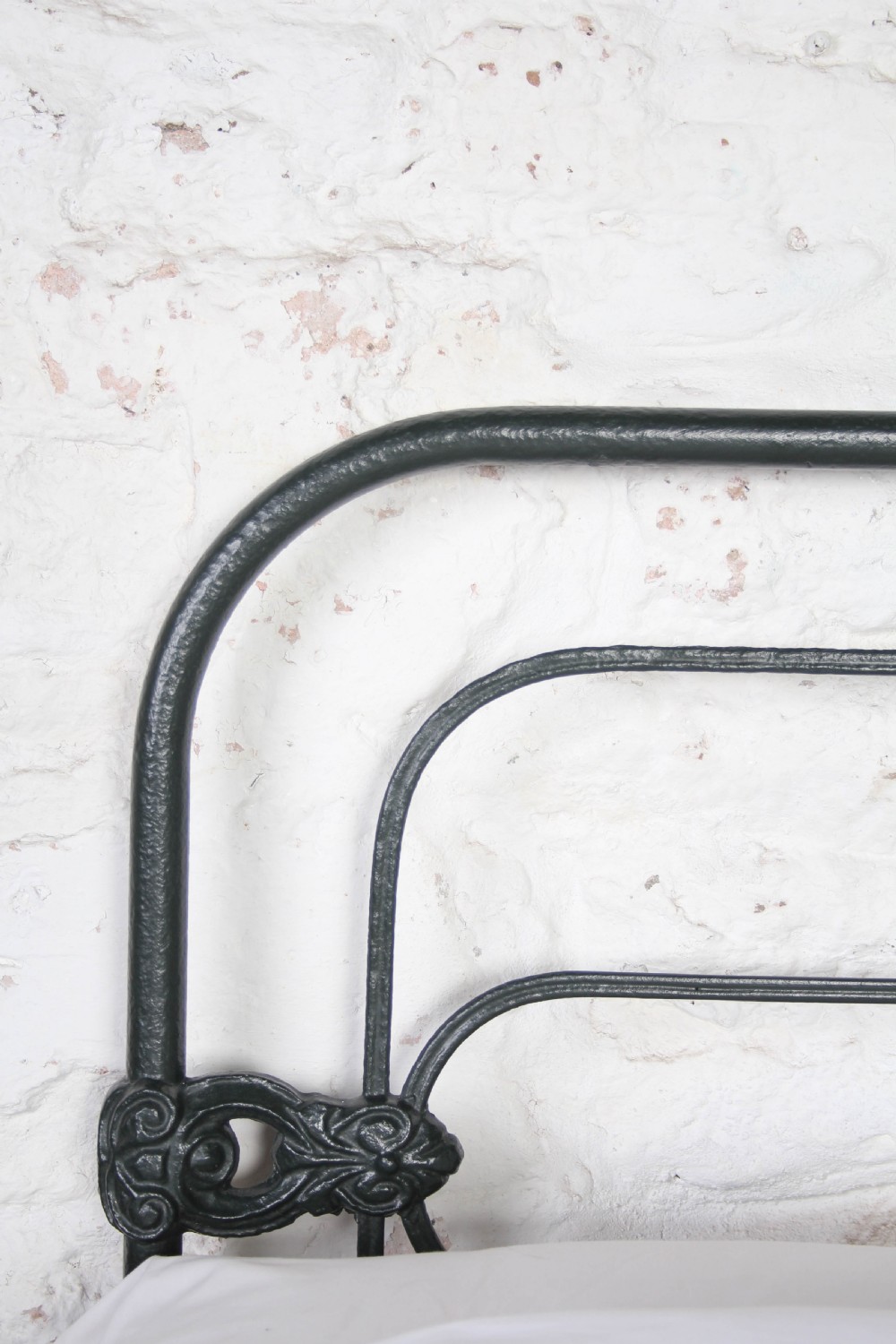 An antique king-size black cast iron bed frame featuring a curved tubular headboard with central cast details and no footboard. View VII