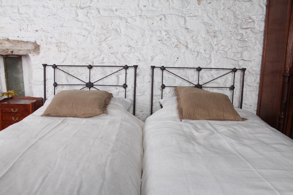 A pair of dark Victorian wrought iron single beds with geometric headboards and footless frames. View IV